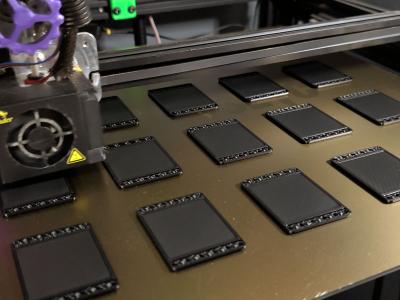 FDM 3D printer producing a batch of black textured panels layer by layer